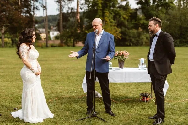 Bernd steht zwischen dem Brautpaar und spricht